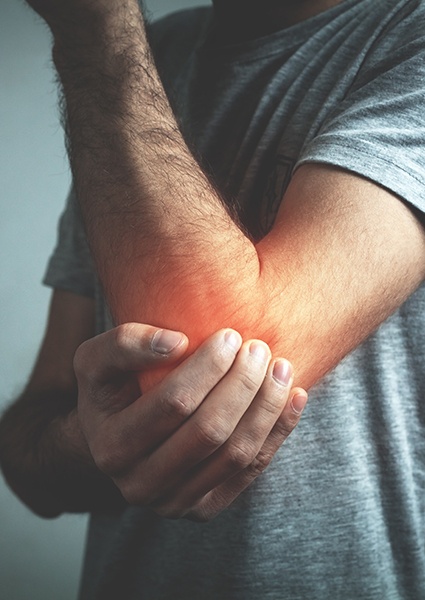 Person holding arm in pain before interventional spine injection