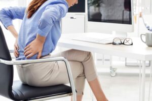 Woman sitting at her desk, suffering from back pain