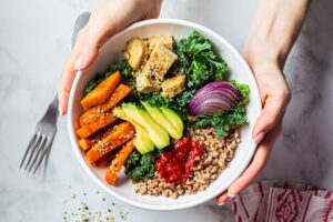 Two hands holding a bowl of healthy food, viewed from above