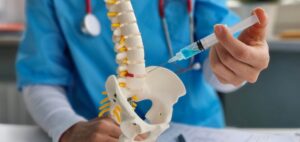 Doctor using spine model to demonstrate pain management injection 
