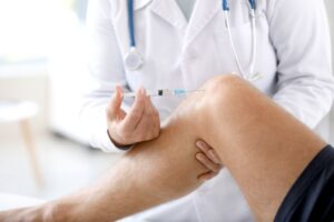 Doctor placing injection in patient’s knee 