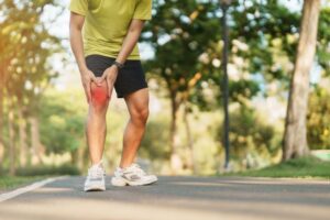 Athlete experiencing knee pain while exercising outdoors
